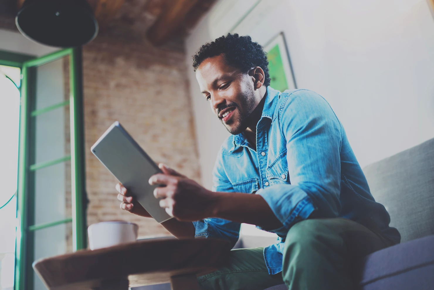 Man smiling while looking at a tablet